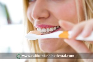 Portrait of pretty young blonde woman cleaning her teeth.